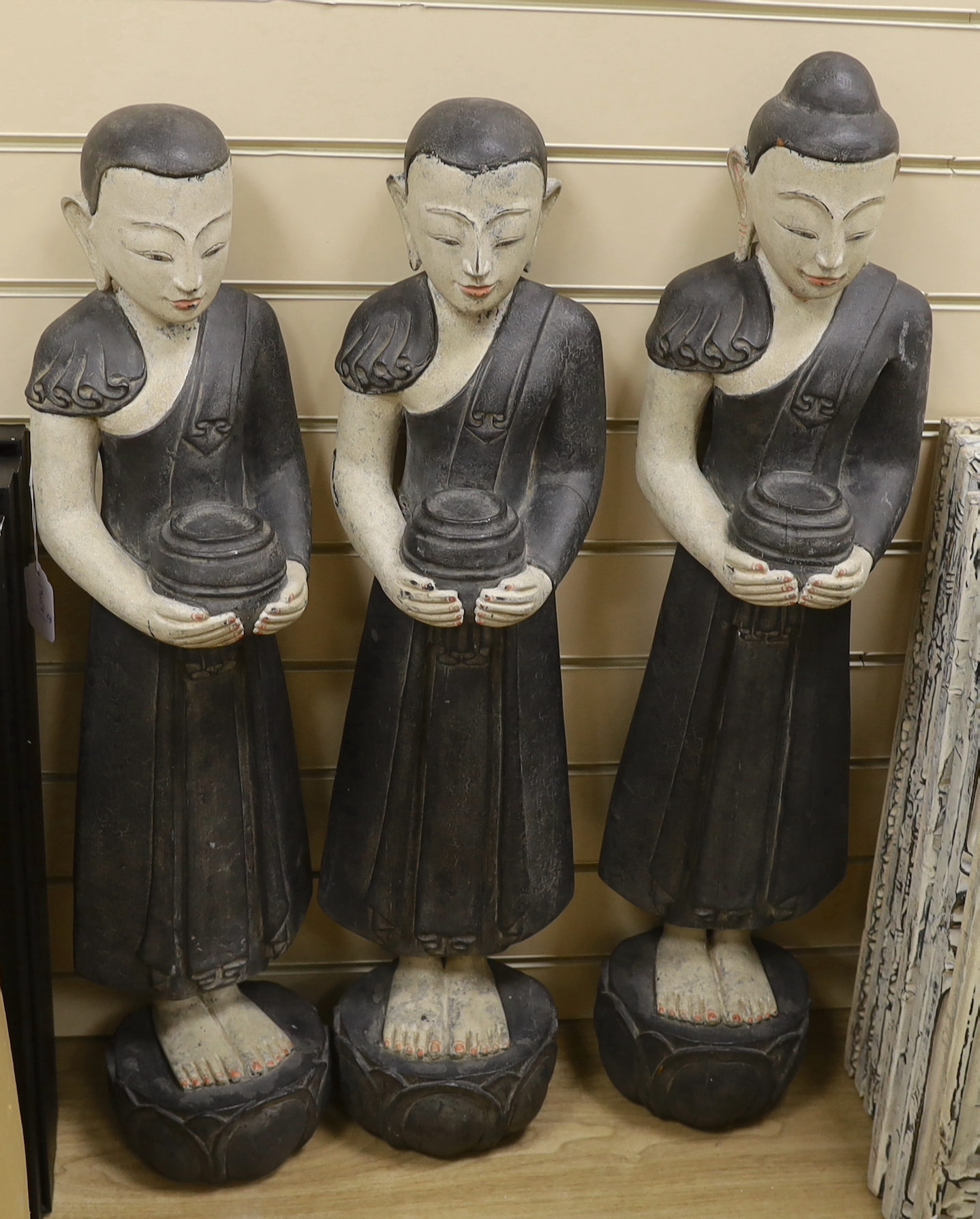 Three floor standing Thai carved wooden deities, 84cm high
